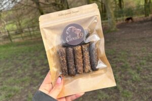 Cloud K9 Rabbit Sausages in hand outside in a field